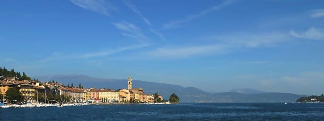 Trip Kreuzfahrten beliebte Urlaubsziele am Gardasee -  Mit einer Fläche von 370 km² ist der Gardasee der größte See Italiens. Es liegt am Fuße der Alpen und erstreckt sich über drei Staaten: Lombardei, Venetien und Trentino. Die maximale Tiefe des Sees beträgt 346 m, er hat eine längliche Form und sein nördliches Ende ist sehr schmal. Dort ist der See von den Bergen der Gruppo di Baldo umgeben. Du trittst aus deinem gemütlichen Hotelzimmer und es begrüßt dich die warme italienische Sonne. Du blickst auf den atemberaubenden Gardasee, der in zahlreichen Blautönen schimmert - von tiefem Dunkelblau bis zu funkelndem Türkis. Majestätische Berge umgeben dich, während die Brise sanft deine Haut streichelt und der Duft von blühenden Zitronenbäumen deine Nase kitzelt. Du schlenderst die malerischen, engen Gassen entlang, vorbei an farbenfrohen, blumengeschmückten Häusern. Vereinzelt unterbricht das fröhliche Lachen der Einheimischen die friedvolle Stille. Du fühlst dich wie in einem Traum, der nicht enden will. Jeder Schritt führt dich zu neuen Entdeckungen und Abenteuern. Du probierst die köstliche italienische Küche mit ihren frischen Zutaten und verführerischen Aromen. Die Sonne geht langsam unter und taucht den Himmel in ein leuchtendes Orange-rot - ein spektakulärer Anblick.